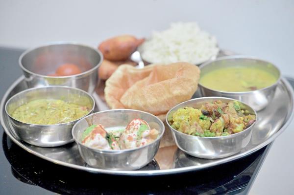 Arti’s celebratory vegetarian dishes include (clockwise from top right) jeera rice, lauki chana dhal, aloo gobi, dahi vada, paneer makhni, gulab jamun and malpua.