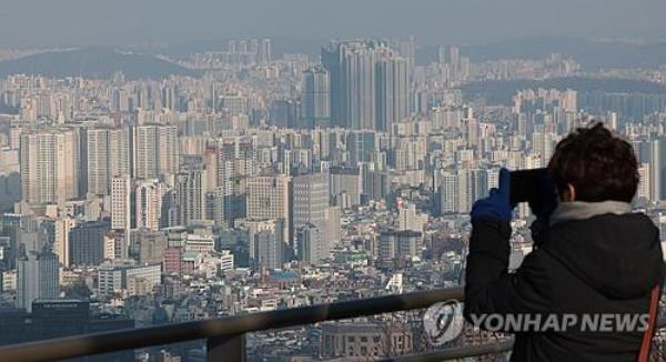 A woman takes a picture of skyscrapers along the Han River from Namsan Observatory in Seoul, in this file photo taken Dec. 20, 2023. (Yonhap)